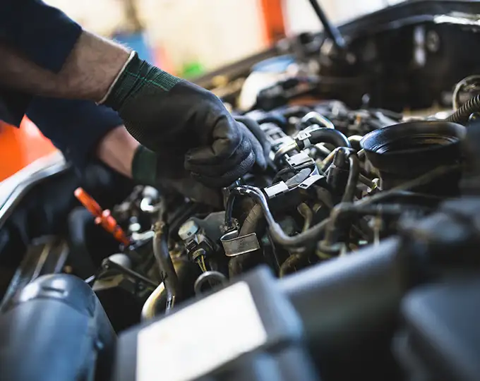 mechanic doing a tune-up on car with hands on engine doing repair